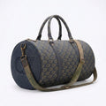 A cylindrical duffel bag with a dark navy blue monogram pattern, featuring dark gray handles, a matching monogram canvas body, a dark navy side panel with an embossed logo, and an olive green shoulder strap.